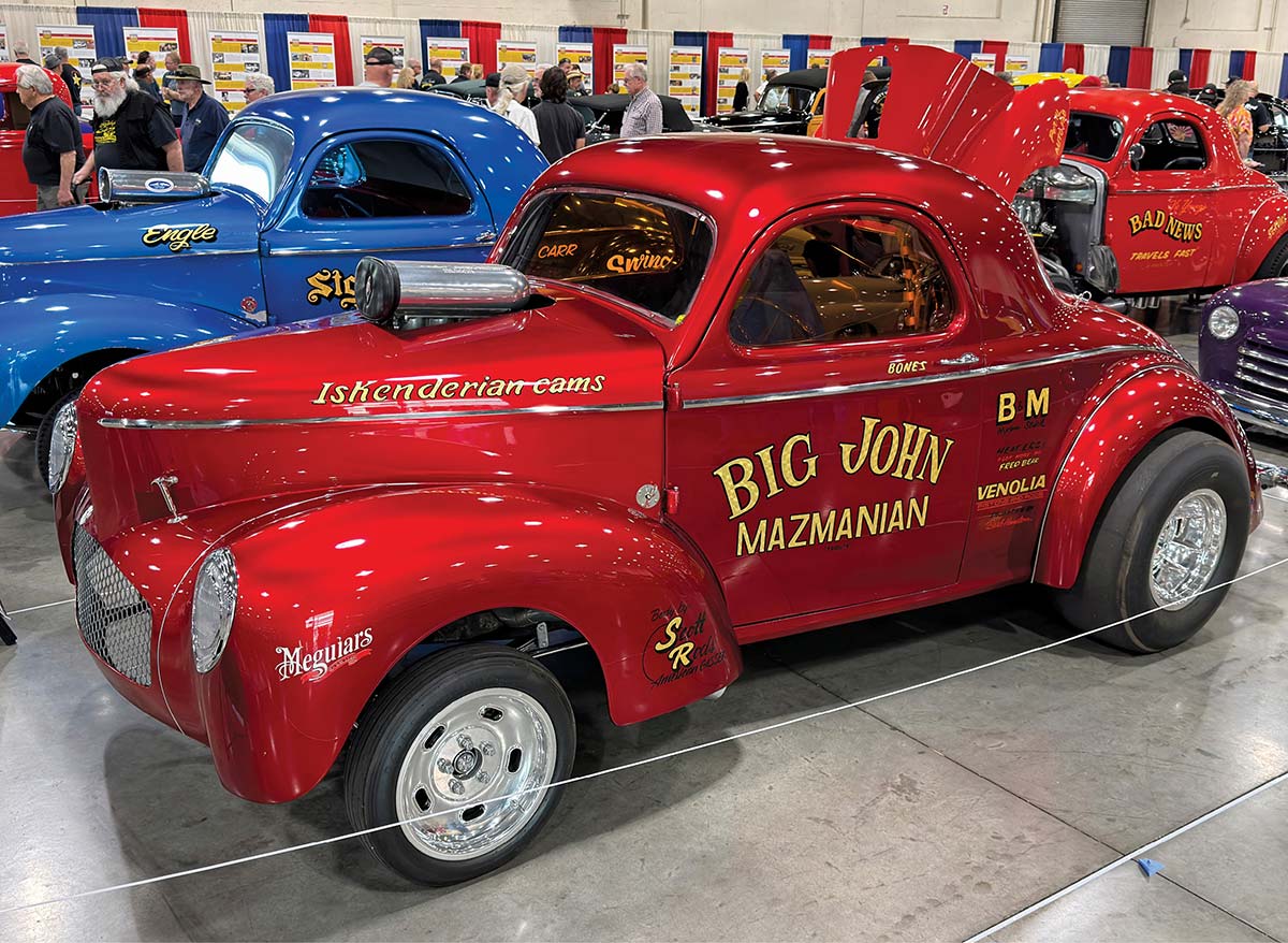 1941 Ford Coupe vibrant red with custom paint, lettering, and a lowered stance alongside other classic hot rods