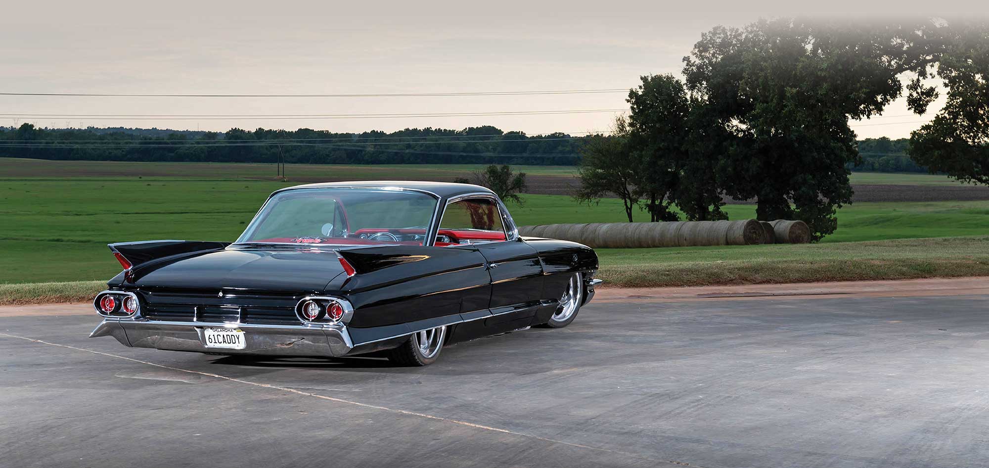 Black customized 1961 Cadillac lowrider with a bright red interior and large custom wheels