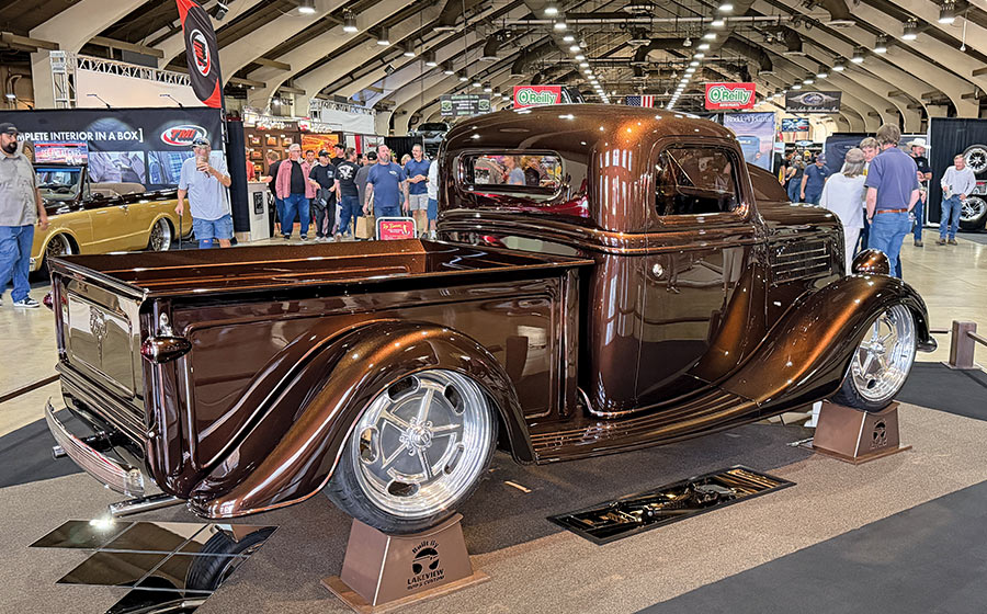 1936 Ford custom pickup truck rear three quarter view with polished billet wheels at indoor car show