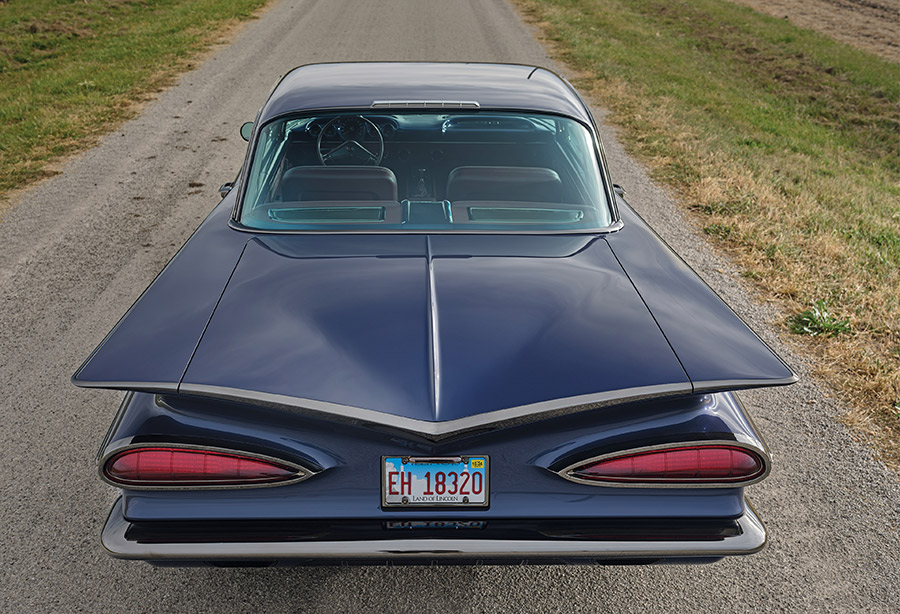 Rear view of the Impala on a rural road showing tailfins.