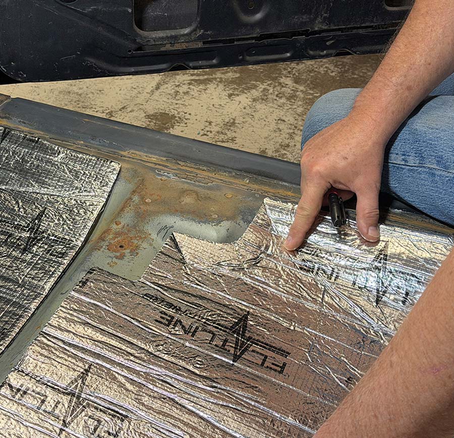 Hand pressing precut insulation piece into car floor pan.