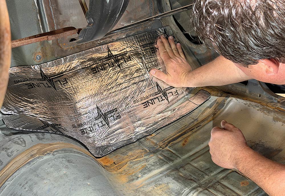 Smoothing out insulation material over car flooring contours.