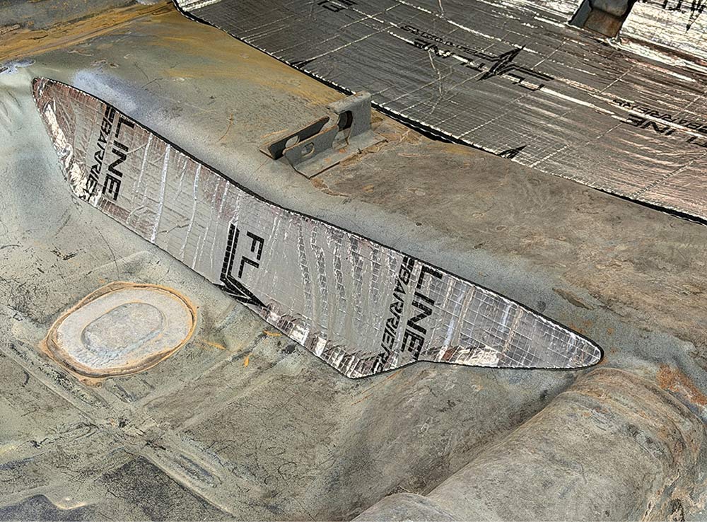 Installing insulation on the rear seat footwell kick panel.