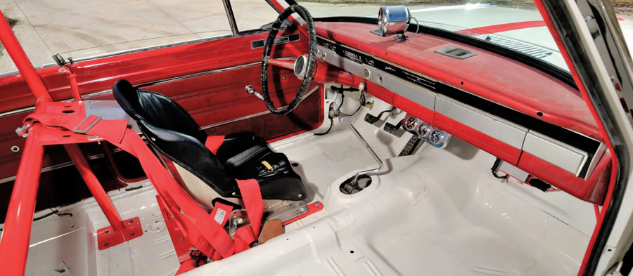 Red and white interior of a vintage race car featuring a single bucket seat.