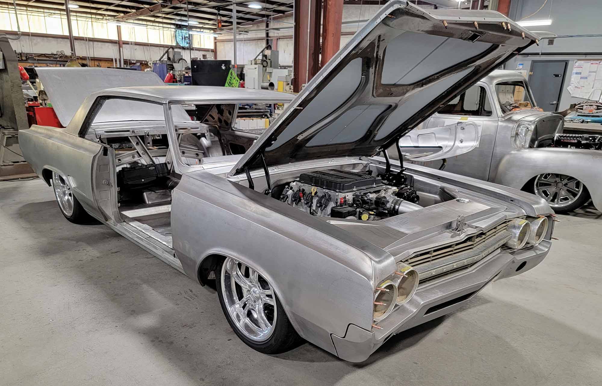 Bare metal 1965 Oldsmobile Cutlass with hood open.