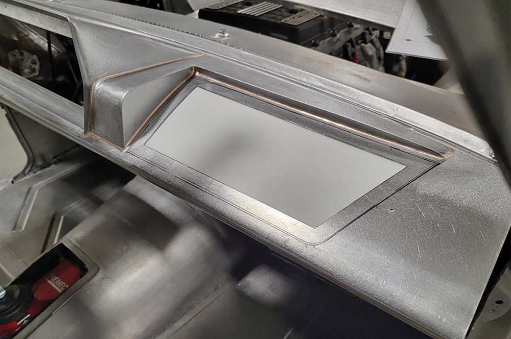 Rectangular opening cut in dash top for glovebox storage.