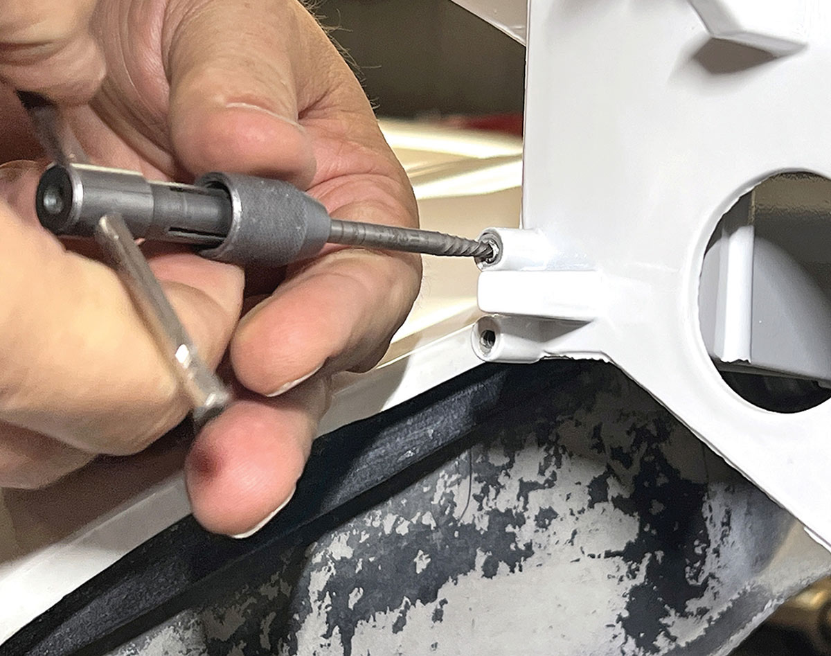 Using a tap and handle to clean mounting hole threads.