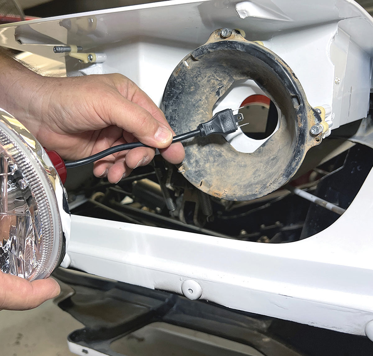 Checking wiring harness compatibility inside the headlight housing.