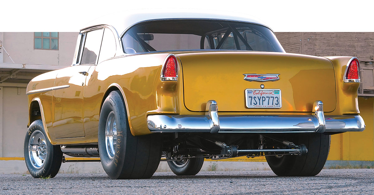 Rear view of a gold 1955 Chevy Bel Air gasser showing large slick tires.