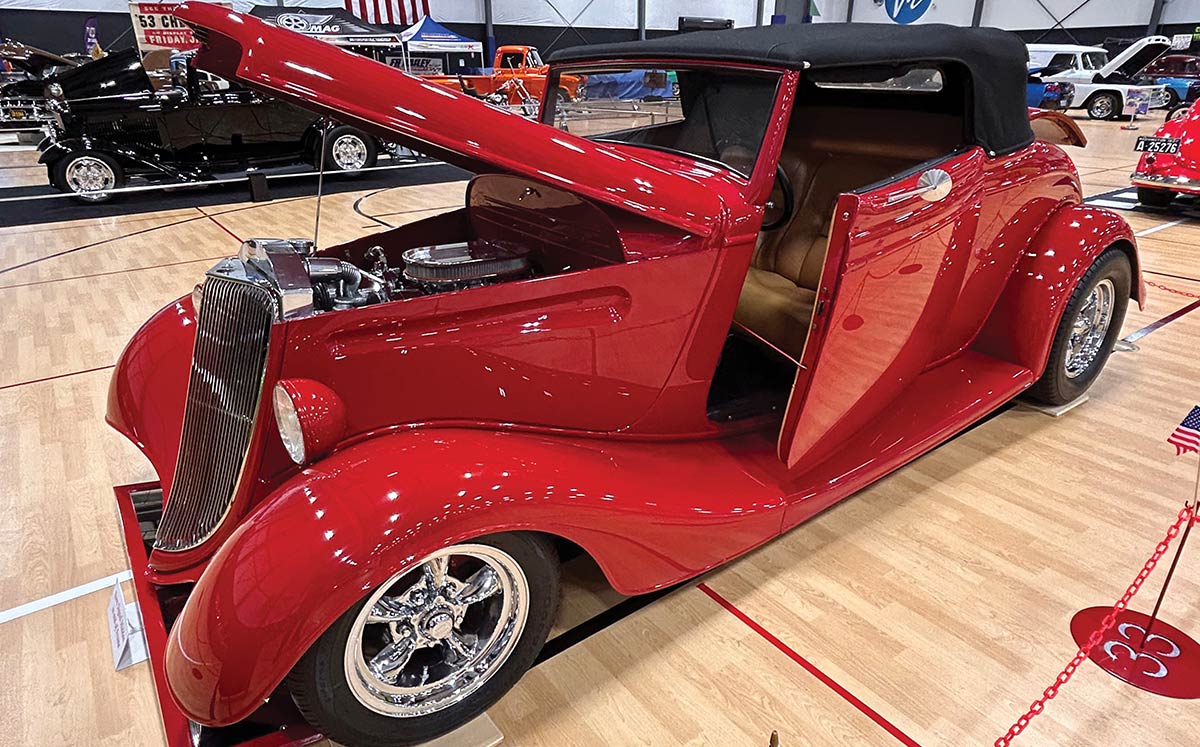Red 1933 Ford cabriolet with top down on display