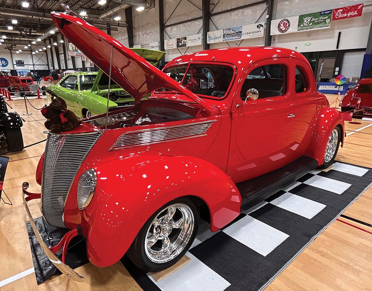 Red 1937 Ford coupe with open hood on display