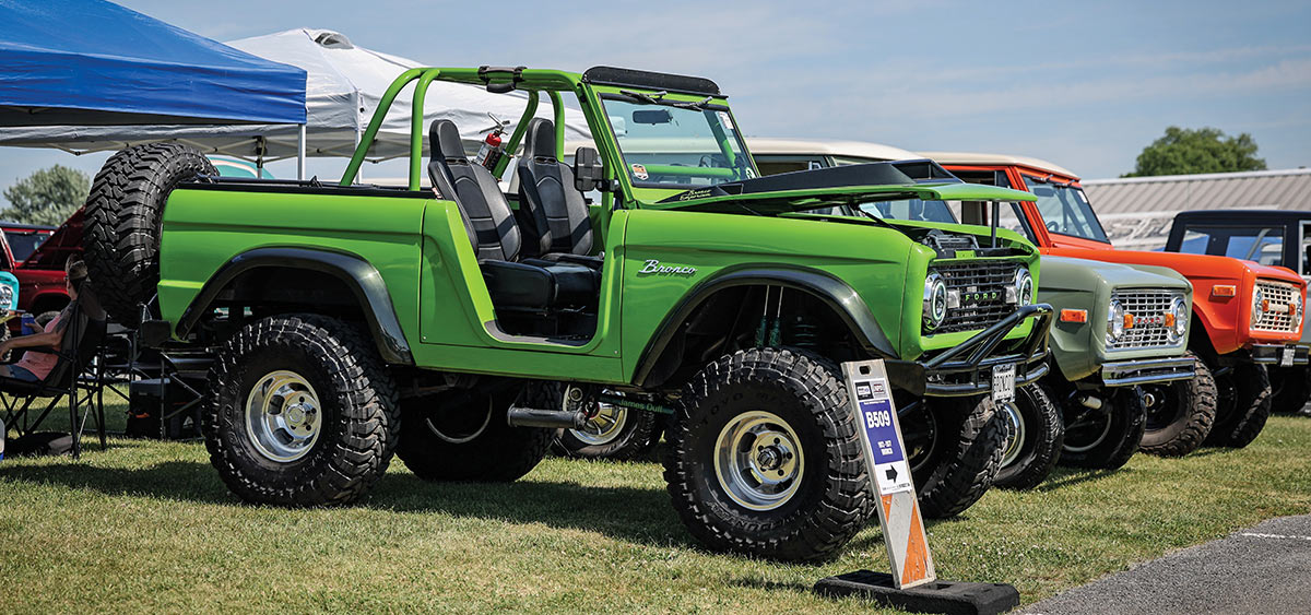 Lifted green early Ford Bronco on display.